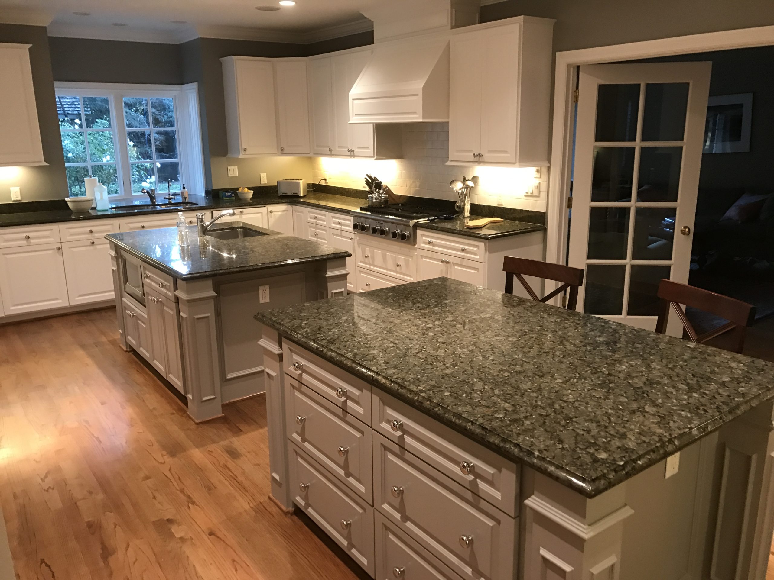 A modern kitchen in San Jose featuring white cabinets and granite countertops, showcasing GruberPainting's expert craftsmanship.